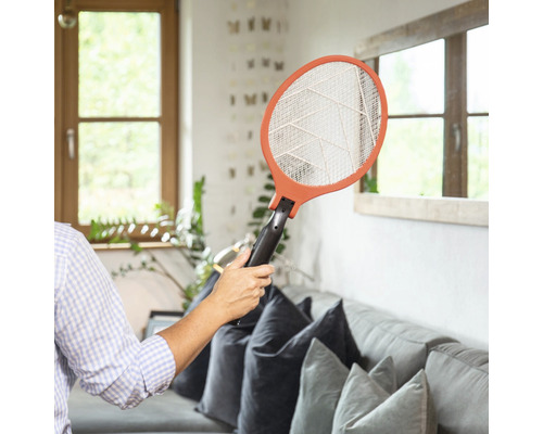 Persoon houdt elektronische vliegenmepper in de woonkamer vast