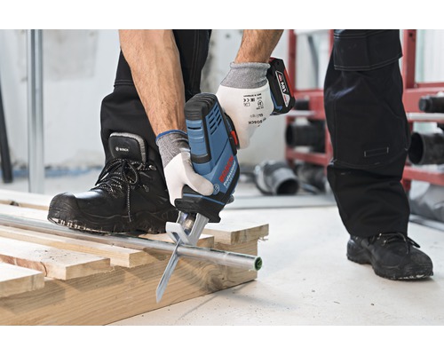 Accuzaag die een pijp doorsnijdt op een houten constructie.