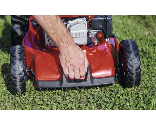 Man start een gazonmaaier op een grasveld.