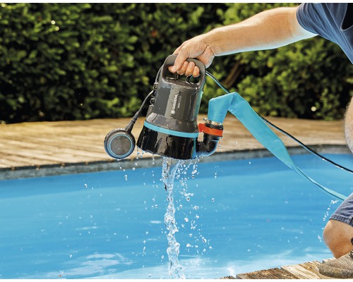 Een Gardena vuilwaterpomp wordt boven een zwembad gehouden terwijl er water uit stroomt.