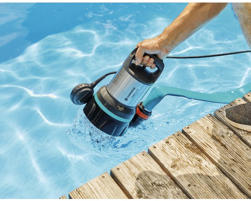 Een persoon gebruikt een Gardena vuilwaterdompelpomp 7000/D om een zwembad leeg te pompen.