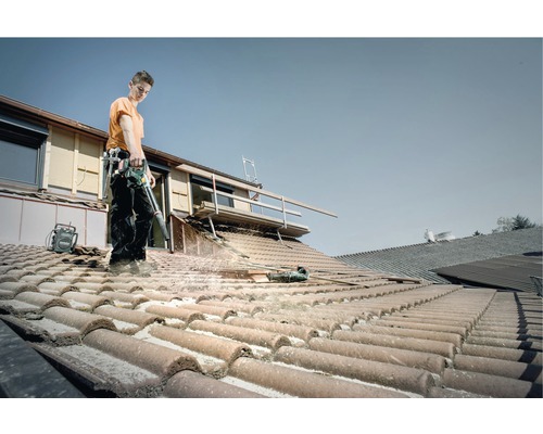 Ambachtsman reinigt dak met accu bladblazer