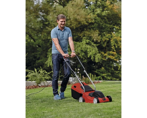 Man maait gazon met een rode elektrische grasmaaier in de tuin.