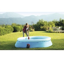 Vrouw gebruikt een dompelpomp om water uit een opblaasbaar zwembad in de tuin te verwijderen.