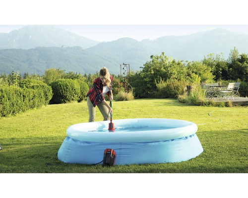 Vrouw gebruikt een dompelpomp om water uit een opblaasbaar zwembad in de tuin te verwijderen.