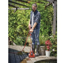 Man reinigt houten terras met terrasreiniger in de tuin