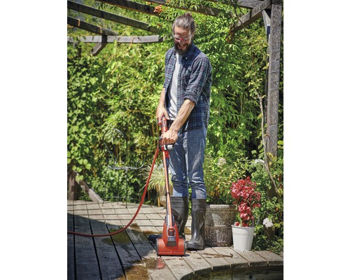 Man reinigt houten terras met terrasreiniger in de tuin