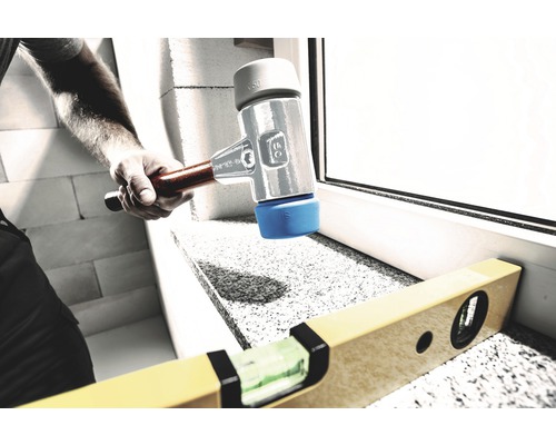 Ambachtsman werkt met een rubberen hamer en een waterpas aan een vensterbank.