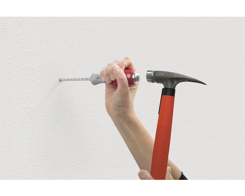 Een persoon slaat met een hamer en plug een gat in een muur.