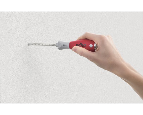 Een hand houdt een schroevendraaier met diepteaanslag van Wiha tegen een muur.