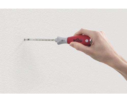 Een hand schroeft met een Wiha schroevendraaier een schroef in de muur.