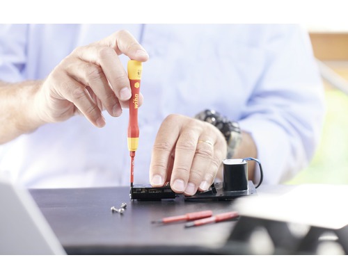 Ambachtsman werkt met schroevendraaier aan elektronisch apparaat