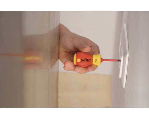 Een man schroeft met een Wiha schroevendraaier een stopcontact vast.