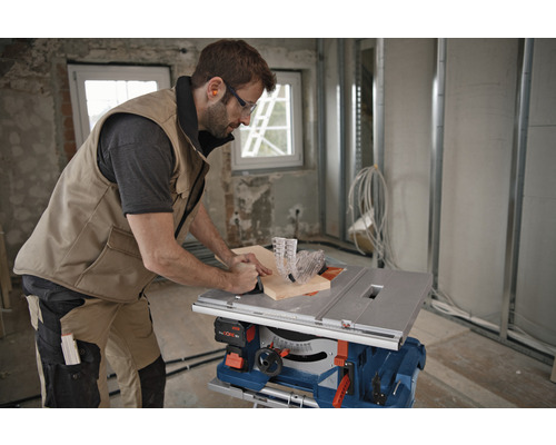 Ambachtsman gebruikt een tafelzaag om hout te zagen in een ruwbouw.