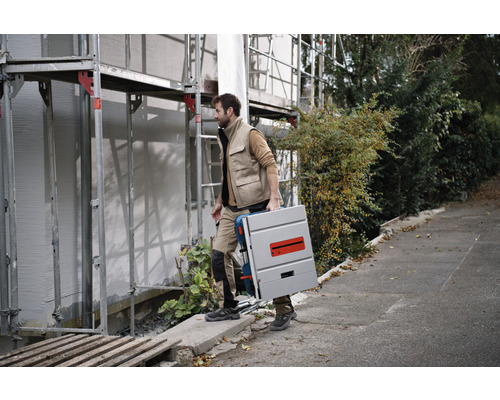 Een man draagt een tafelzaag op een bouwplaats.