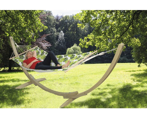 Vrouw ontspant in een hangmat met houten frame en bladmotief in de tuin.