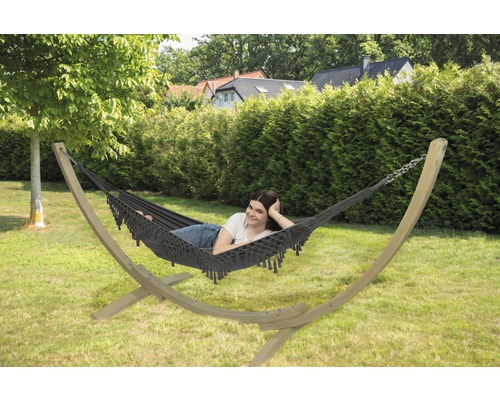 Hangmat met houten frame in de tuin met een vrouw erin.