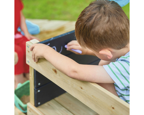 Jongen tekent met krijt op een bord aan een zandbak