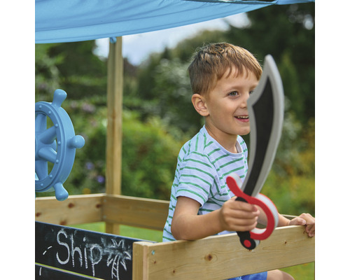 Jongen speelt met een speelschip en een speelgoedzwaard in de tuin