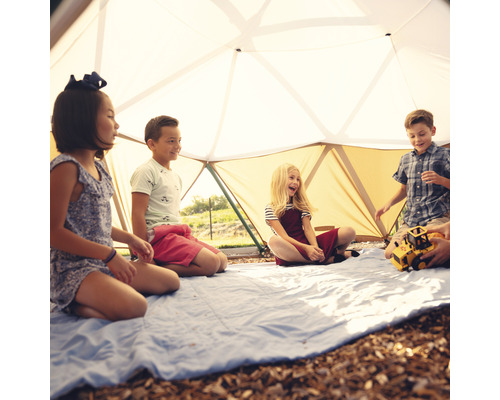 Kinderen spelen in een geodetische koepeltent op een blauw deken.