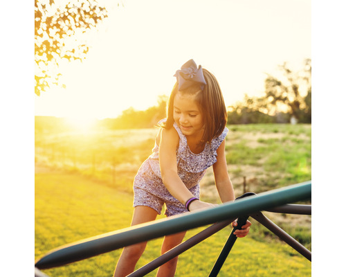 Meisje speelt op een klimrek buiten