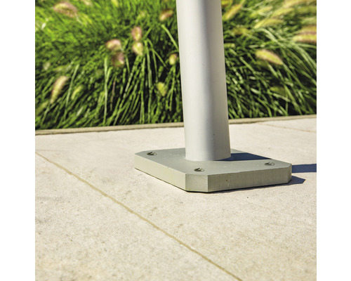 Detail van een zilverkleurige tuinlamp met vierkante basis op een stenen vloer