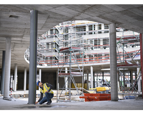 Bouwvakker meet een stalen kolom op een bouwplaats.