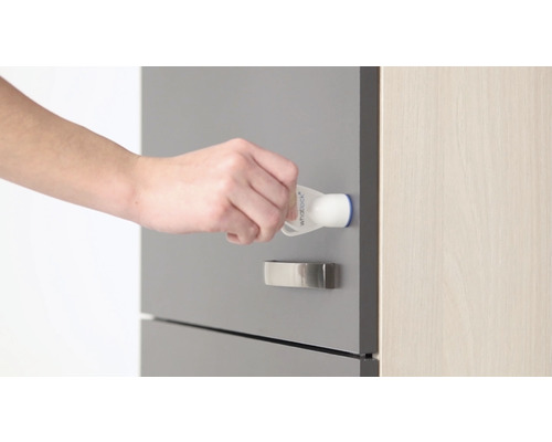 Een hand bevestigt een kinderslot op een lade.