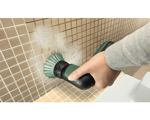 Een persoon reinigt tegels met een elektrische reinigingsborstel