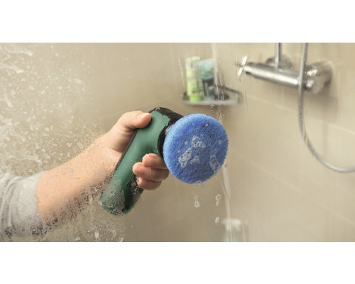 Een persoon reinigt een douchewand met een elektrische reinigingsborstel.