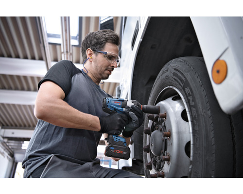 Een man gebruikt een accuslagschroevendraaier om een wiel aan een voertuig te bevestigen.