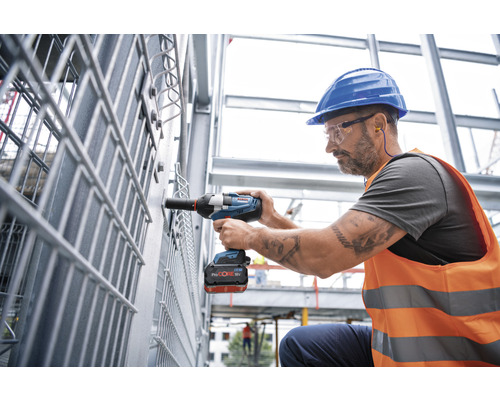 Een bouwvakker gebruikt een accuslagschroevendraaier op een bouwplaats.
