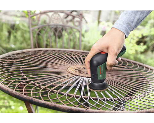 Een persoon reinigt een metalen tuintafel met een schuurmachine van Bosch