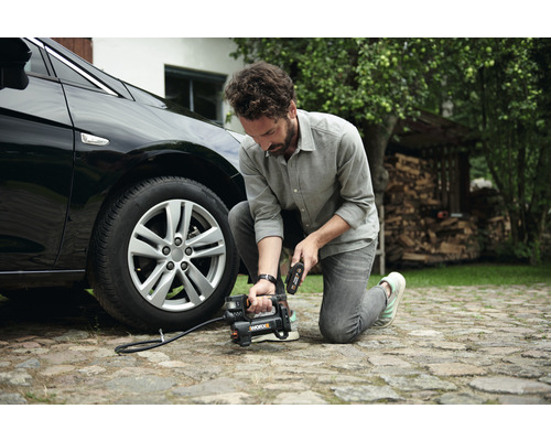 Man vult autoband met een draagbare compressor.