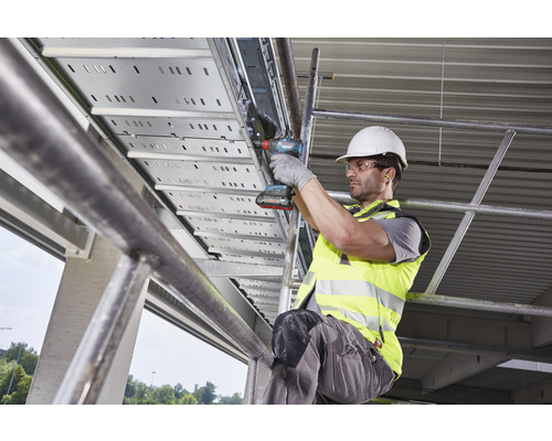 Een man monteert met een accuschroevendraaier een kabelgoot.