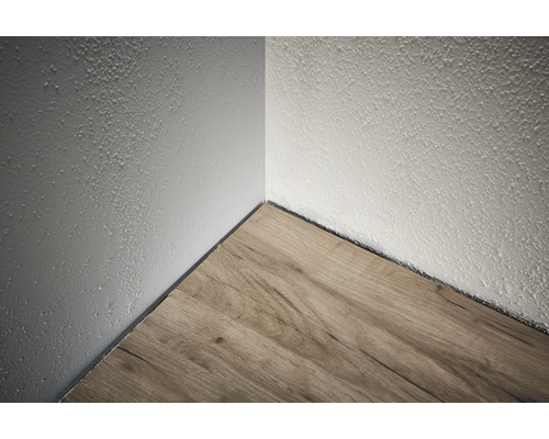 Hoek van de kamer met laminaatvloer en ruwe pleistermuur