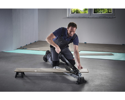 Man snijdt laminaat met een laminaatsnijder.