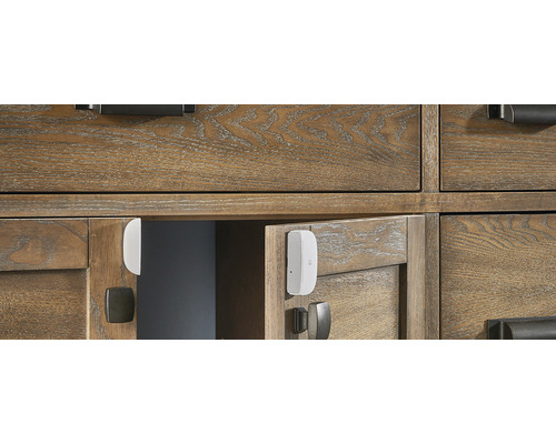 Slimme deur- en raamsensor op een houten kast