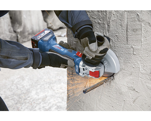 Accu haakse slijper in gebruik bij het snijden van metalen staven op een betonnen muur