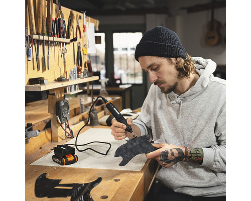 Man bewerkt een werkstuk met een multifunctioneel gereedschap op een werkbank.
