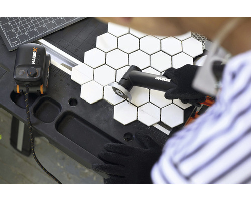 Iemand snijdt zeshoekige tegels met een gereedschap van Worx