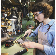 Vrouw werkt met een doorslijpmachine in een werkplaats.