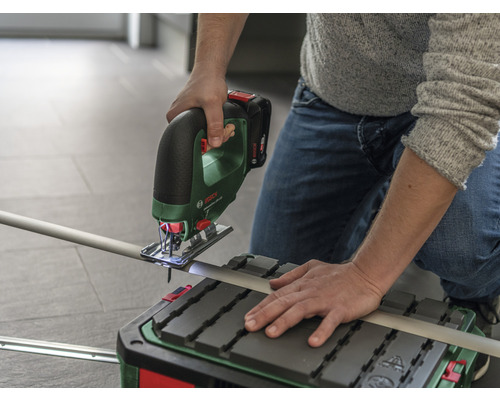 Een persoon zaagt een buis met een accusleutelzaag op een zaagtafel.