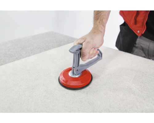 Tegelzetter met zuignap die een tegel optilt