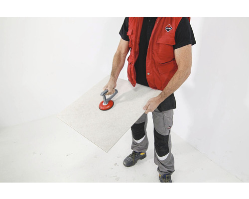 Een man draagt een tegel met een zuignaplift.