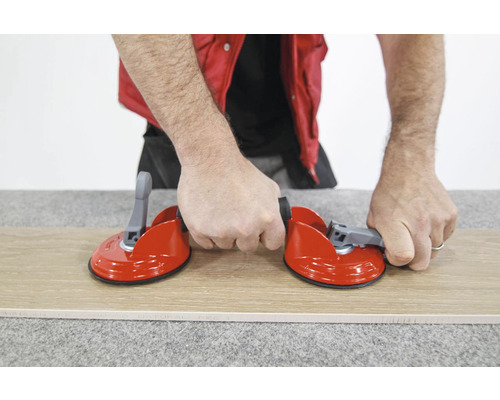 Man hanteert tegelzuiger met twee zuignappen op tegel