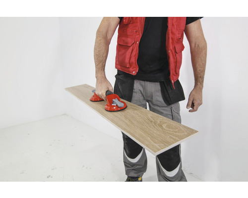 Een persoon vervoert een tegel met zuignappen.