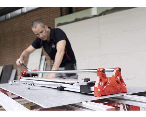 Ambachtsman aan het werk met een tegelsnijder om een tegel op maat te snijden