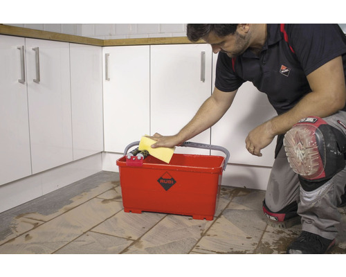 Tegelzetter maakt tegels schoon met spons en tegelzetemmer