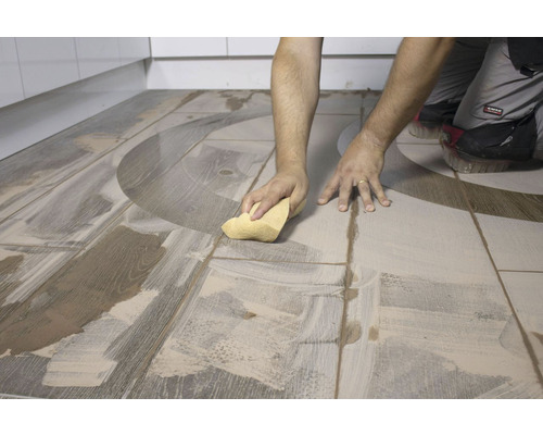 Tegelzetter reinigt vloertegels na het leggen